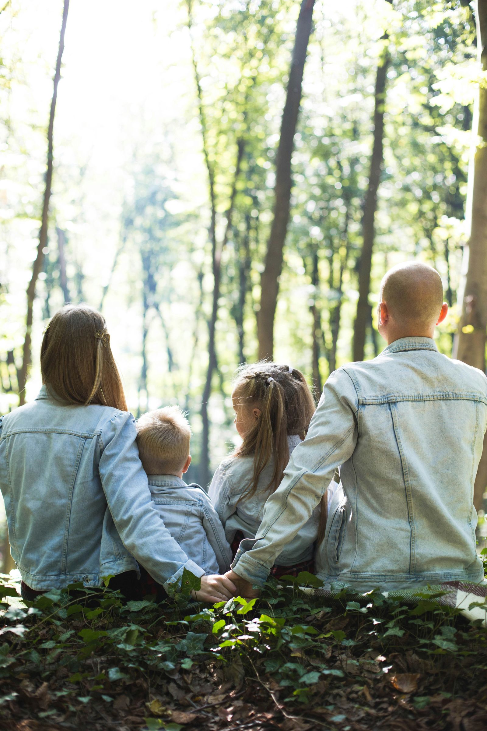 A healthy family sat on a log in a forest